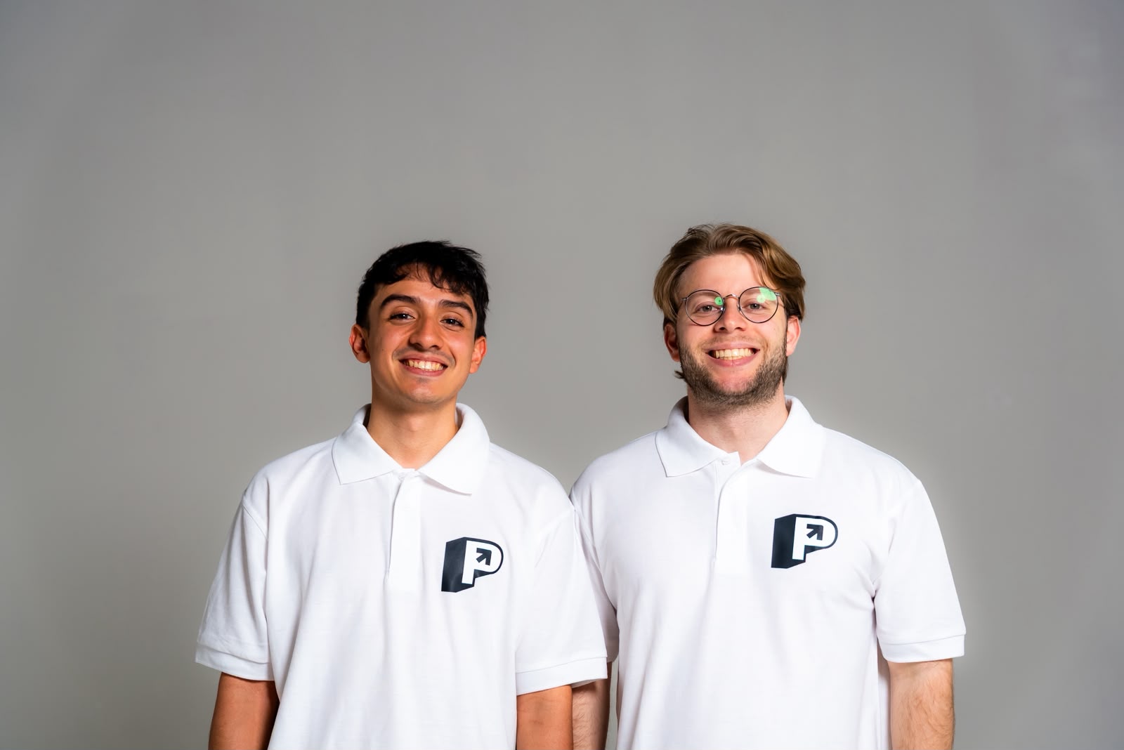 Luis Quiodettis y Alex Abadi, fundadores de PupiloHub, con polo blanco de la empresa sobre fondo gris de estudio